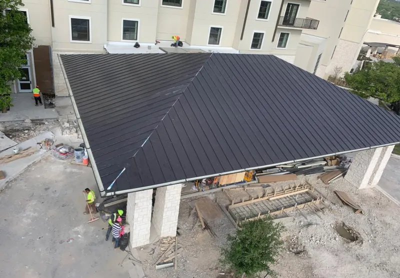 Metal roofing installation team working on a commercial building in Webster